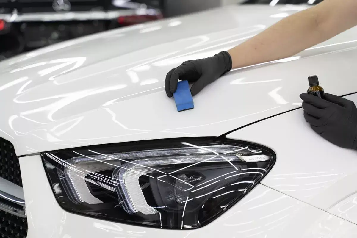 Profesionálna aplikácia keramickej ochrany laku na kapotu vozidla s profesionálnymi nástrojmi v auto detailingovom centre Redes Cars